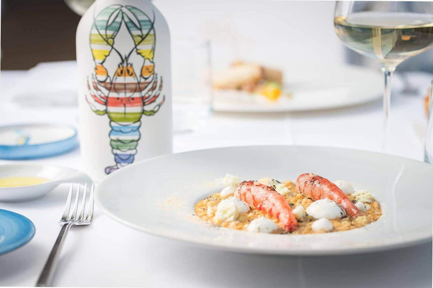 Rainbow lobster design olive oil on table, paired with lobster dish, elegant presentation showcasing handcrafted Italian ceramic and premium extra virgin olive oil