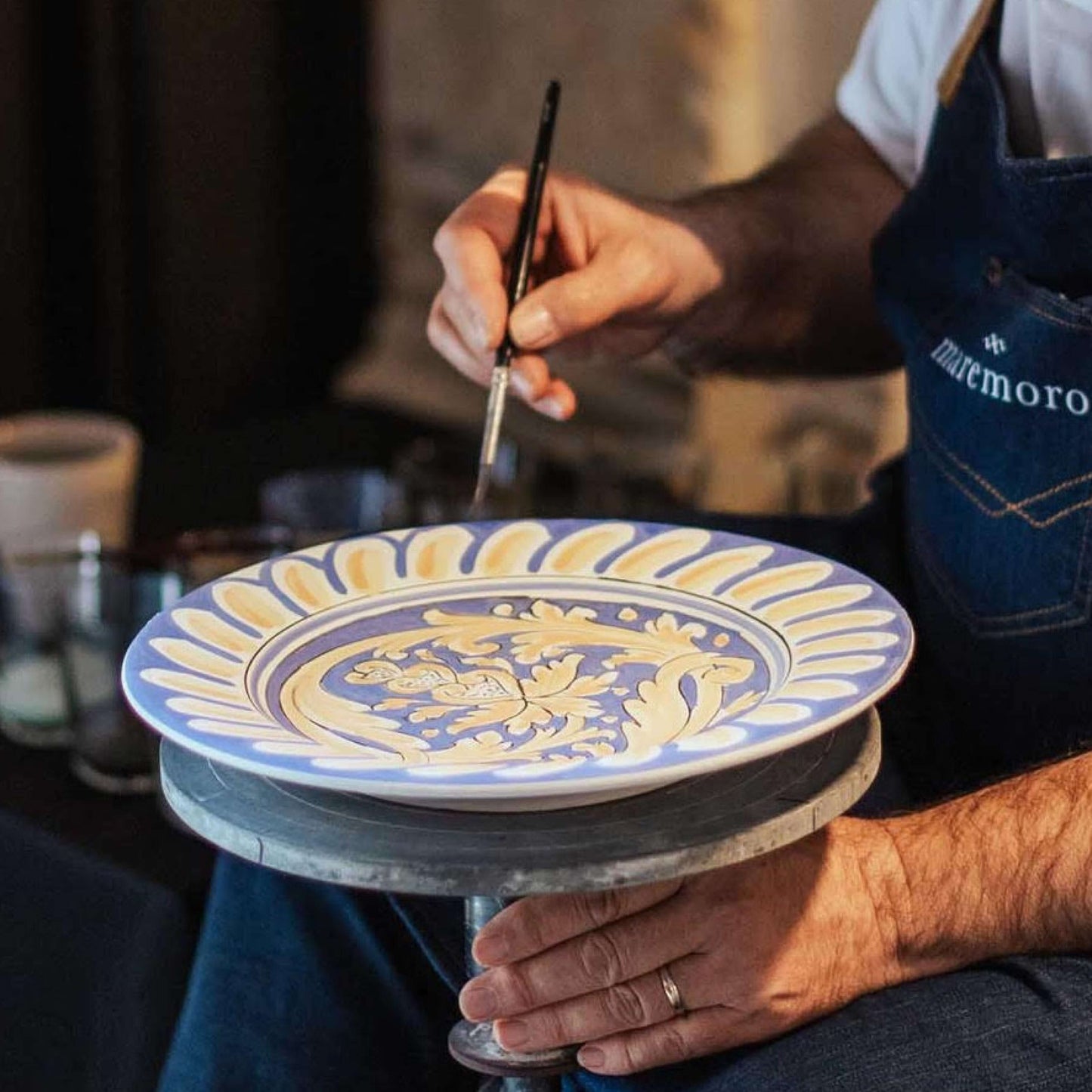 Artisan hand painting top of ceramic plate, no decals, showcasing traditional Sicilian craftsmanship and freehand artistry on handmade plates